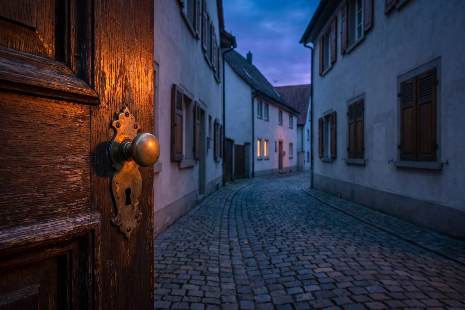 Symbolbild: alte Holztür mit Messingknauf und Schlüsselloch an einer gepflasterten Gasse – Einsatzgebiet Schlüsseldienst Tuttlingen