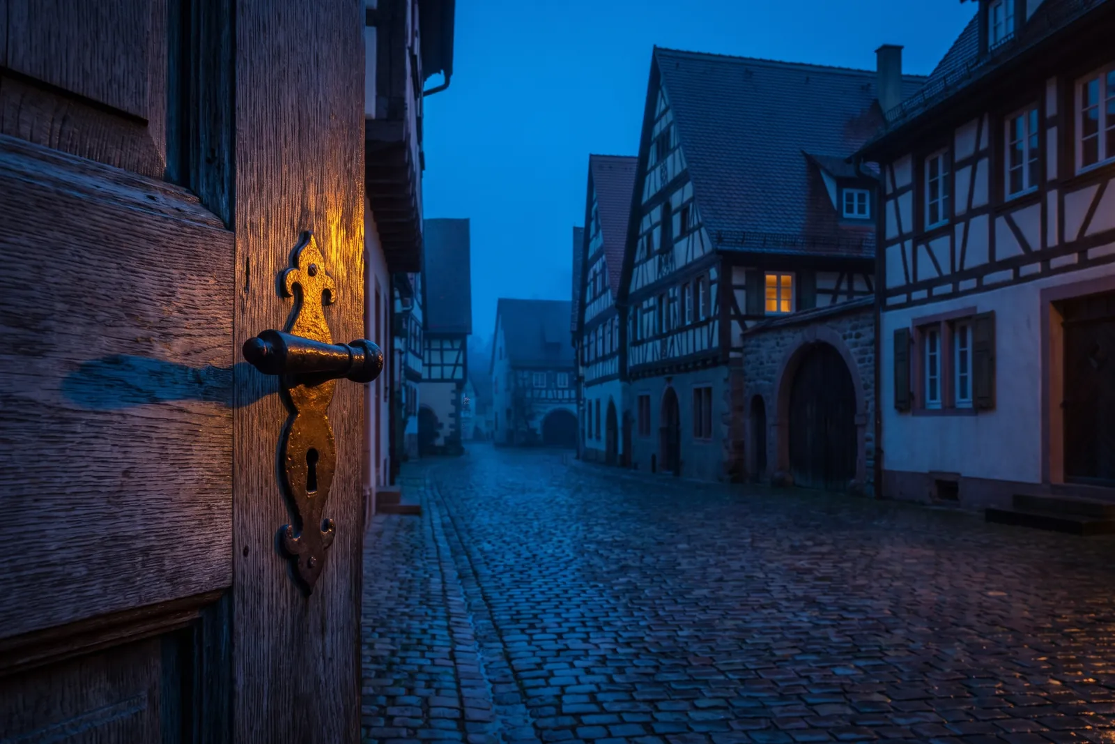 Symbolbild: Bohlentür mit schmiedeeisernem Drücker vor Fachwerkhäusern im Nebel – Einsatzgebiet Schlüsseldienst Villingen-Schwenningen