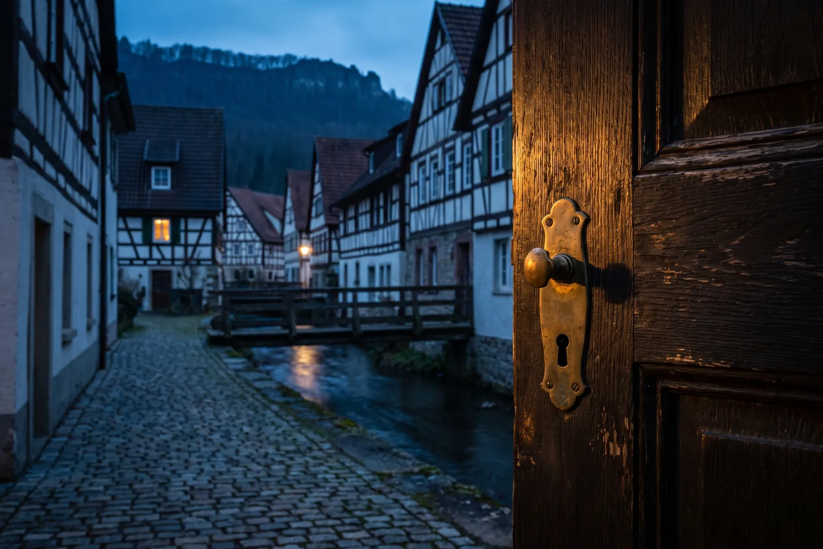 Symbolbild: Haustür mit Messingknauf an einer Gasse am Bach, Fachwerkhäuser und bewaldeter Albtrauf im Hintergrund – Einsatzgebiet Schlüsseldienst Balingen
